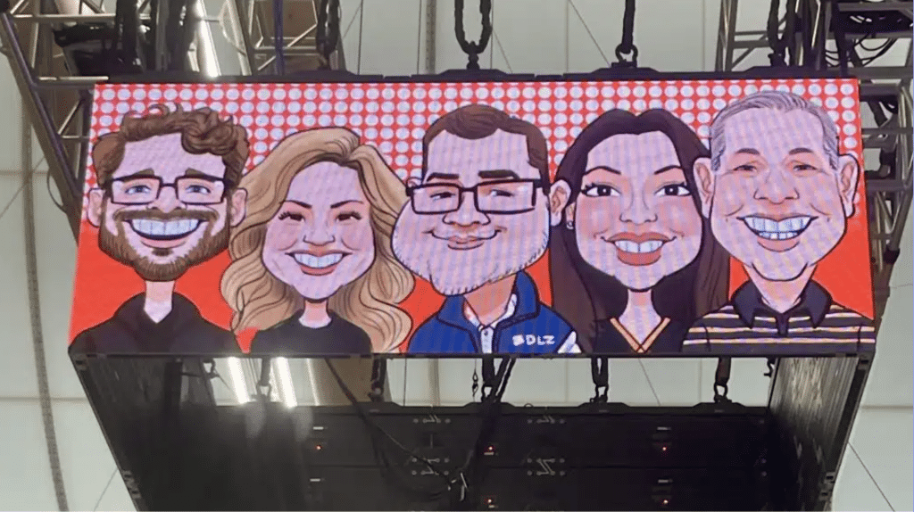 Group caricature drawing of five colleagues on branded event backdrop
